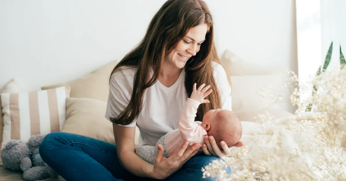 Mutter mit Tochter im Arm im Sonnenuntergang auf einem Strand