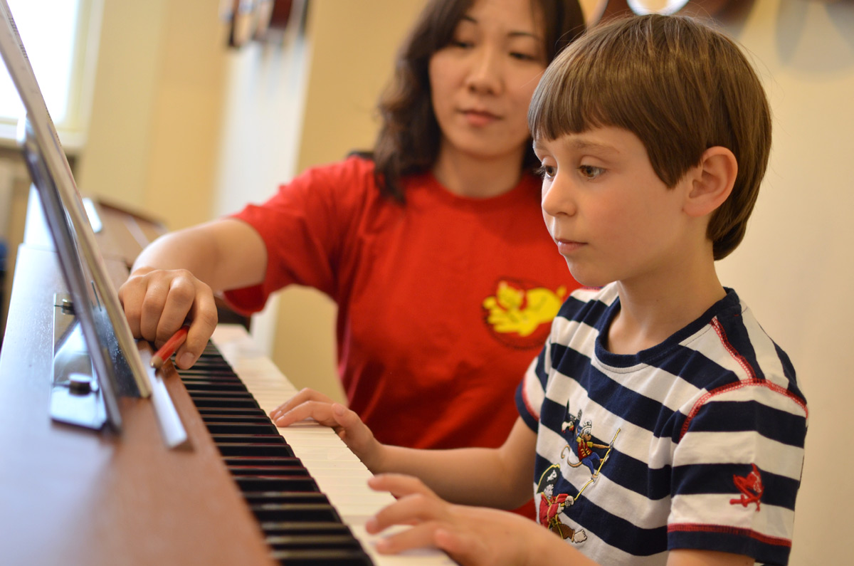 Junge spielt mit Lehrerin Klavier