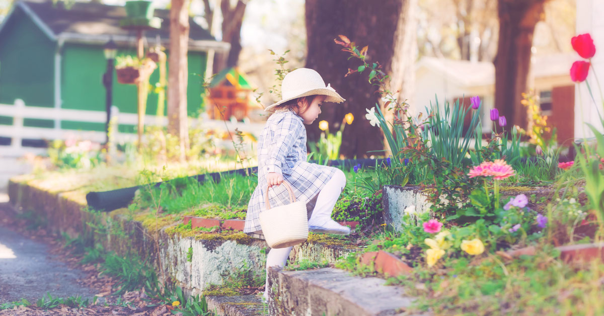 Mädchen im in einem Blumengarten mit einem Korb in der Hand