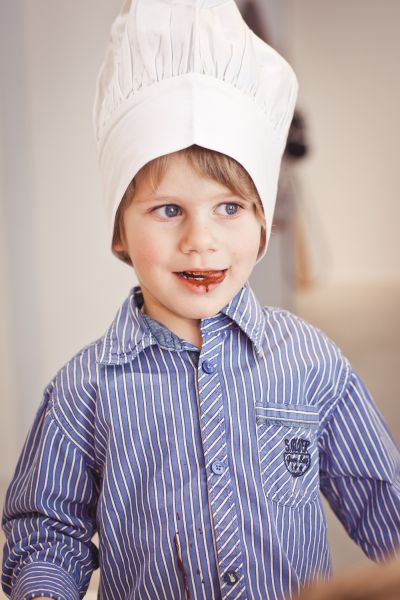 Bub mit weißer Kochmütze, Schokolade auf den Lippen