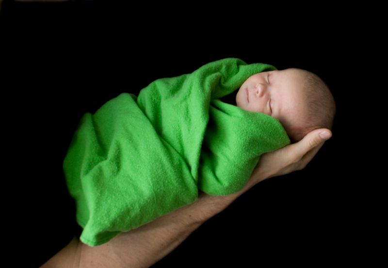 Baby in ein grünes Handtuch gehüllt, eine Hand haltet es