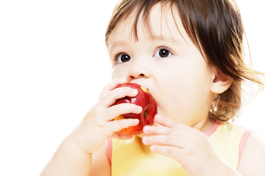 Kleines Mädchen beißt in einen Apfel