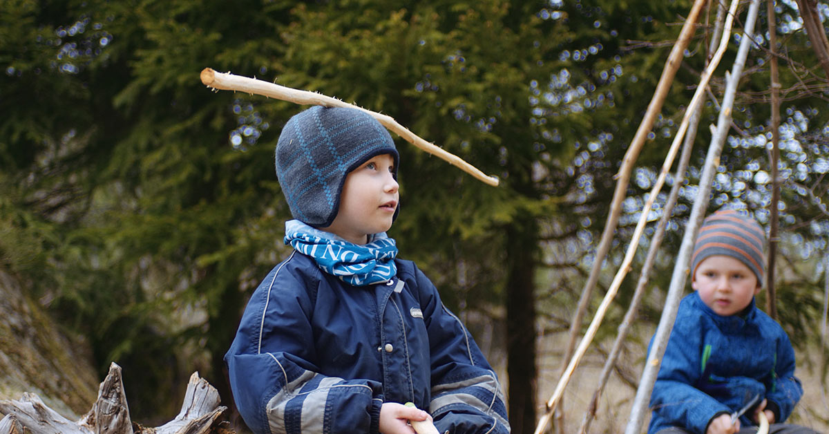 Kindheit Filmstill - Junge trägt einen blauen Ast am Kopf im Wald