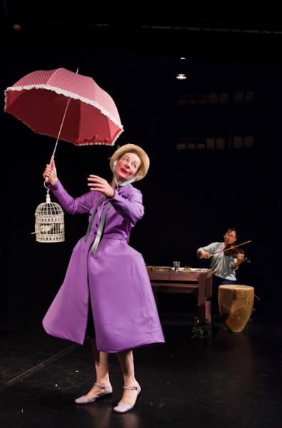 Foto aus dem Theaterpsiel - Frau mit Schirm und langem violettem Kleid