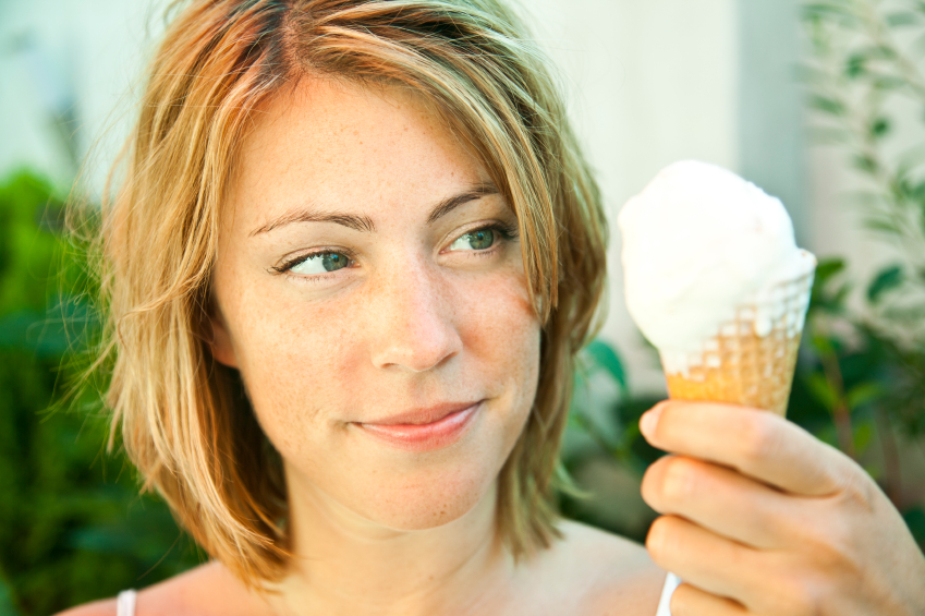 Eine blonde Frau betrachtet ein Eis mit wohlwollen.