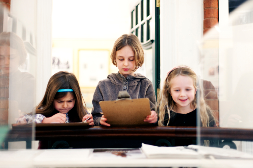 3 Mädchen lernen an einem Tisch im Museum