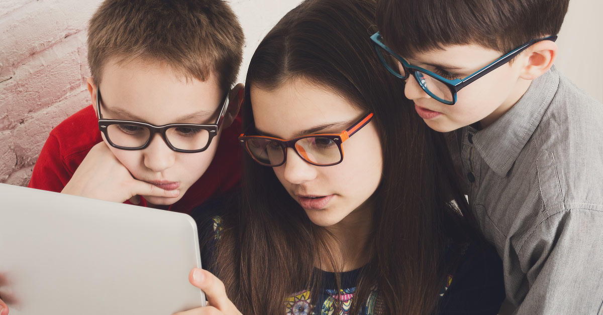 Drei kurzsichtige Kinder schauen auf ein Tablet