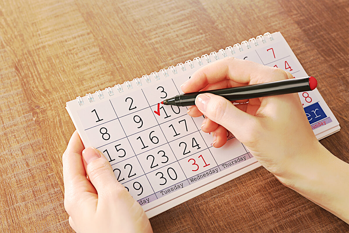 Eine Frauenhand die ein Kalenderzelle mit dem Geburtsdatum ausfüllt