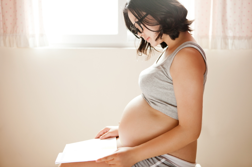 Eine schwangere Mutter liest in Informationsunterlagen